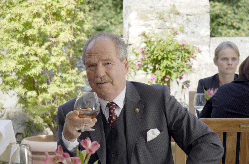 Dr. Hans Hibbold (Friedrich von Thun) ist mit dem Cognac und den Bemühungen seines Freundes Schweigert sehr zufrieden. – Bild: ORF/​ZDF