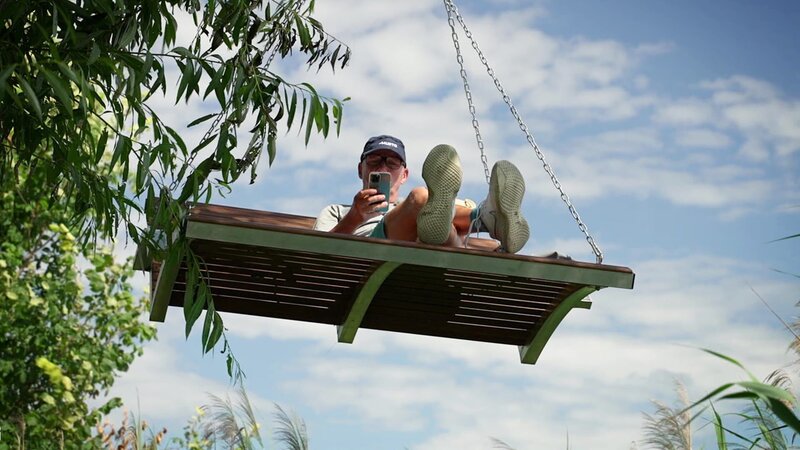 Ein Mann ruht sich auf einer Schaukel aus – Bild: Warner Bros. Discovery