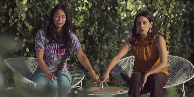 Tracy (Minh-Khai Phan-Thi, l.) und Mari (Maryam Zaree, r.) nehmen via Ouija-Board Kontakt zu Oma Thuy auf und bekommen Antworten auf ungeklärte Fragen. – Bild: ZDF