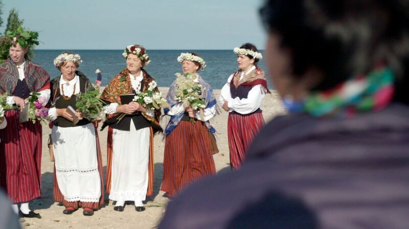 Am Kap Kolka, wo Ostsee und Rigaer Bucht wild aufeinandertreffen, kämpft sich Dzeneta Marinska durch Sturmwarnungen, Gästeansturm und Roggenküchlein. Die Campingplatzbetreiberin, Köchin und stolze Livin bereitet sich auf die kürzeste Nacht des Jahres vor – auf ein Fest, das Natur, Tradition und Freiheit vereint. Die Mittsommerwende: Für viele Letten ein magischer Moment, für Dzeneta noch mehr. Denn zu Sowjetzeiten war das Kap Sperrgebiet und Mittsommerfeiern hier verboten. Heute wird wieder gesungen, getanzt, gekocht. Dzeneta zeigt ihren Gästen, was es heißt, als Livin mit der Natur zu leben. – Bild: MDR/​Dunja Engelbrecht
