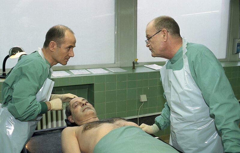 Dr. Robert Kolmaar (Ulrich Mühe, l.) und Prof. Bondzio (Dieter Mann, r.) obduzieren gemeinsam die Leiche von Karl Boventer. – Bild: ZDF