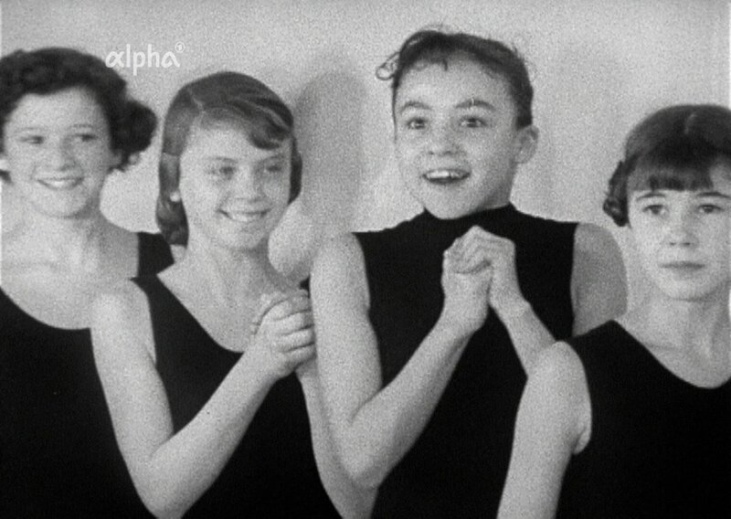 Gezeigt wird in diesem Film von 1958 ein Tag in den Trainingsräumen des Balletts der Bayerischen Staatsoper, die damals noch nicht restauriert war und unverhüllt die Bombenschäden aus dem Zweiten Weltkrieg zeigte. Zuerst trainieren die Erwachsenen, danach die Kleinen, also die Kinder von ungefähr 7 Jahren an. Zu diesen jungen Mädchen kommt dann der Ballettmeister, er sucht für ein neues Stück Tänzerinnen, die auf der Bühne kleine Tauben darstellen sollen. Große Aufregung: Wer darf mitmachen? – Bild: BR