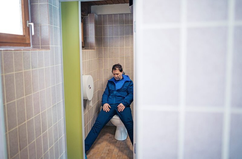 Ein Toter (Komparse) liegt in einer der Toilettenkabinen. – Bild: ARD/​Jenrick Mielke