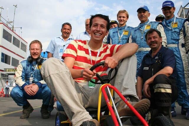 Willi sorgt mit einem Gokart bei den Streckenposten am Norisring in Nürnberg für Spaß. Heute möchte Willi herausfinden, wie man Rennfahrer wird. – Bild: BR/​megaherz gmbh