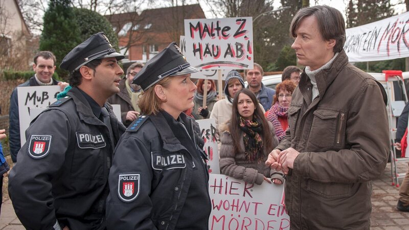 Bäckermeister Mittelbach (Martin Armknecht, r.) ist das Sprachrohr eines aufgewühlten Mobs gegen die Unterbringung des Gewaltstraftäters Zühl in ihrer Nachbarschaft. Claudia (Janette Rauch) und Tarik (Serhat Cokgezen, l.) versuchen zu beruhigen. – Bild: ZDF