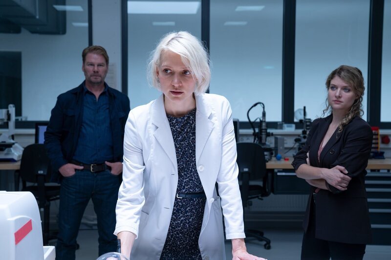 Lissy Krömer (Frida-Lovisa Hamann, M.) interessiert kein Geld, nur Wissenschaft. Können Kommissar Winkler (Kai  Scheve, l.) und Kommissarin Szabo (Lara Mandoki, r.) das glauben? – Bild: ZDF