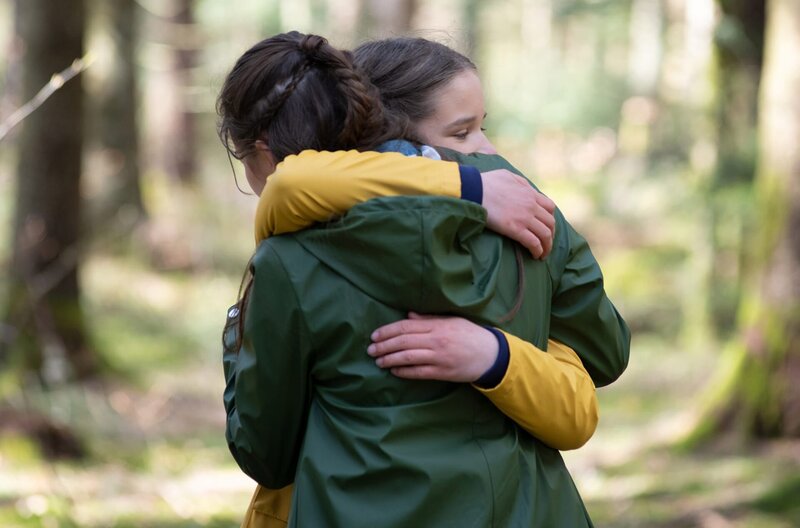 Leo (Phillis Laura Lau, vorn) und Lucy (Paulina Schnurrer, hinten) verabschieden sich unter Tränen – Bild: ARD/​Maria Wiesler
