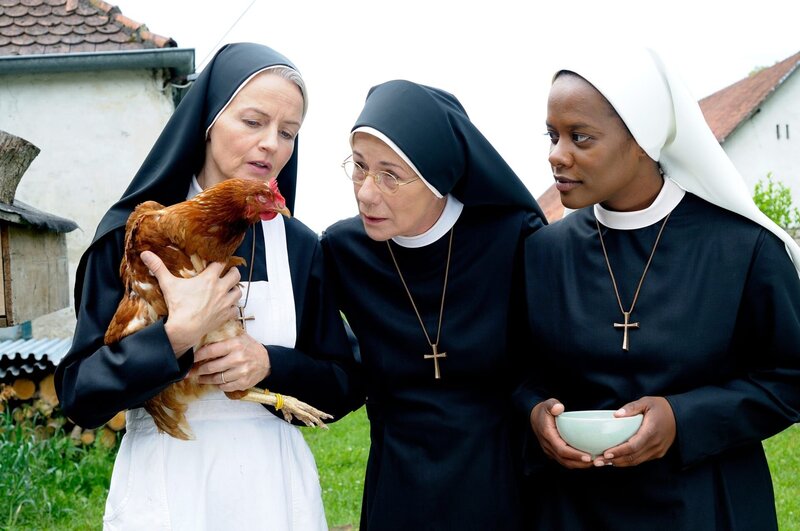 Agnes (Emanuela von Frankenberg, li.) zeigt Felicitas (Karin Gregorek, mi.) und Lela (Denise M’Baye, re.) erstmals, dass Lady Gaga prophetische Kräfte hat. – Bild: ORF/​Kineos/​Jacqueline Krause-Burberg