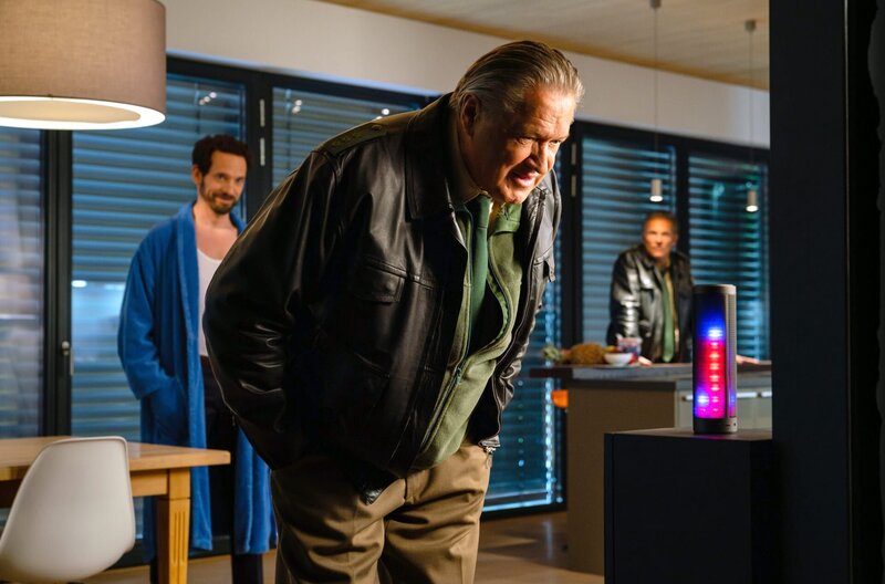 Girwidz (Michael Brandner, v.M.) versucht „Polli“ Dr. Seidls (Markus Andreas Klauk, l.) Geheimnisse zu entlocken (mit Christian Tramitz, r.). – Bild: ARD/​TMG/​Arvid Uhlig