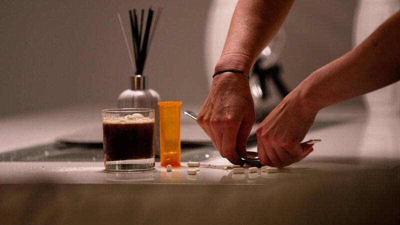 Eine Person zerkleinert die Tabletten und gibt sie in ein Glas mit Getränken. – Bild: zlw /​ Crime + Investigation