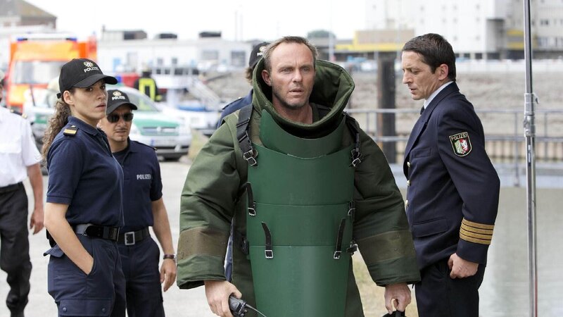 Angespannt verfolgen Conny (Jasmin Gerat, l.), Semir (Erdogan Atalay, 2.v.l.) und Albers (Stefan Gebelhoff), wie sich der Sprengstoffexperte Roloff (Dirk Martens, M.) an die Entschärfung der Bombe macht. – Bild: TVNOW /​ Guido Engels