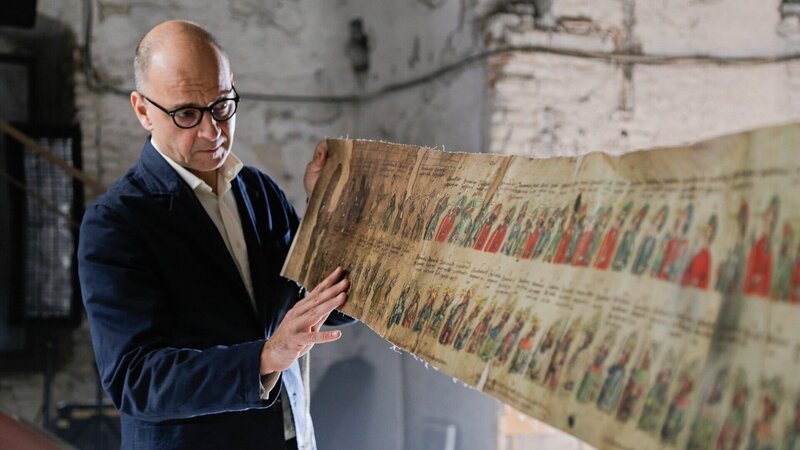 Moderator Paul Matic präsentiert das Papst-Kaiser Rotulus. – Bild: SRF/​Metafilm GmbH