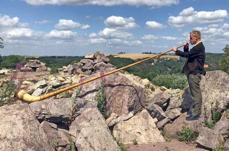 Prof. Andreas Roloff bringt seinen Studenten die Baumarten bei, indem er sie besingt oder bespielt – das Alphorn ist aus Fichte, Roloff erlernte es und spielt es für den Film extra in „Nordamerika“, dem jüngsten Waldteil des Forstbotanischen Gartens – Bild: MDR/​Dirk Schneider