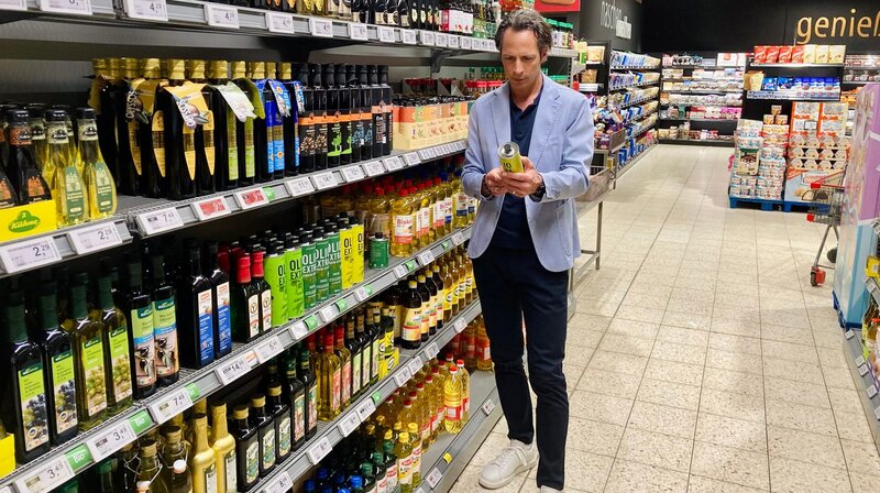 Reporter Jo Hiller vor dem Ölregal in einem Supermarkt. Welche Qualität ein Öl hat, ist nicht immer leicht zu erkennen. – Bild: NDR/​Jennie Radü