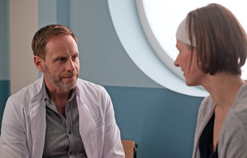 Maria Webers (Annett Renneberg) Entlassung steht bevor und Dr. Kai Hoffmann (Julian Weigend) bietet ihr an, sich um sie zu kümmern. Als Maria ihn daran erinnert, dass sie bei Martin Stein wohnt und das dann eher schwierig werden könnte, bittet Kai sie überraschenderweise zu ihm zu ziehen. – Bild: BR/​MDR/​Saxonia Media/​Robert Strehler