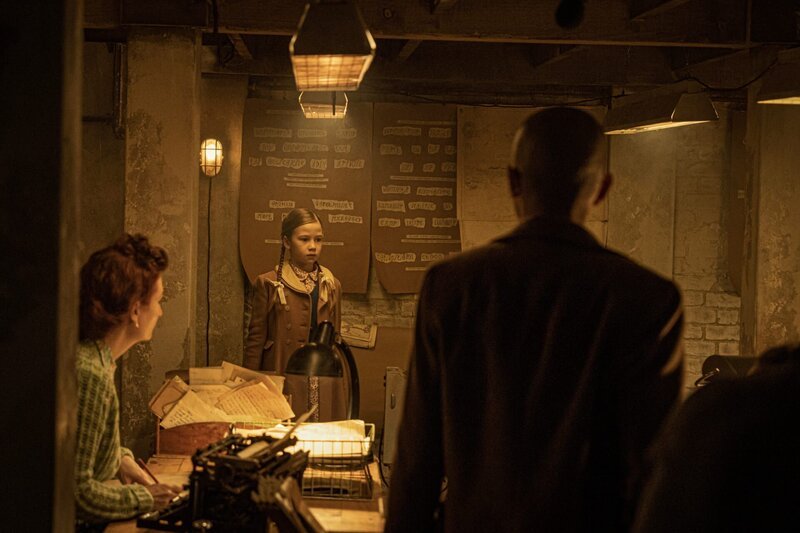 Die junge Miriam (Riona Gallagher, M.) hat viel Zeit im Buchladen verbracht. Die Geschichte ihrer Kindheit spielt im Zweiten Weltkrieg. Sie dreht sich um die Codeknacker-Frauen von Juniper, die im Keller von Dorothy Dangerfields (Bridget Marumo, r.) Buchladen arbeiten. – Bild: ZDF