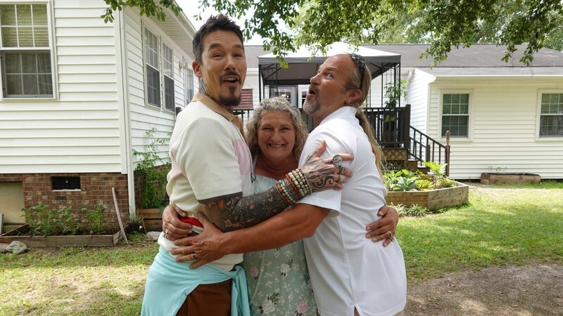 FROM LEFT TO RIGHT: HOST DAVID BROMSTAD POSE FOR A PICTURE WITH LOTTERY WINNERS DEBORAH AND JOHN TEAGUE OUTSIDE OF HOUSE 3, BOTTLEBRUSH BAY – Bild: HGTV US