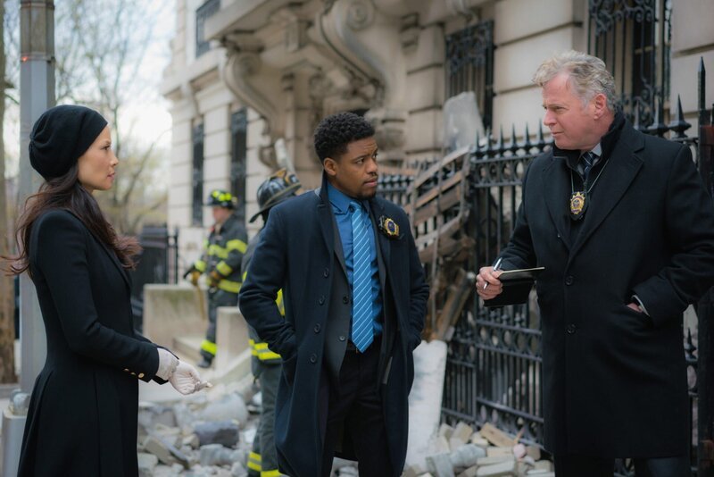 In Morlands Büro geht eine Bombe hoch. Watson (Lucy Liu, l.) und Holmes halten Moriartys Organisation für den Drahtzieher. Doch sie beschließen, das lieber vor Captain Gregson (Aidan Quinn, r.) und Detective Bell (Jon Michael Hill, M.) geheim zu halten und ermitteln auf eigene Faust … – Bild: Michael Parmelee