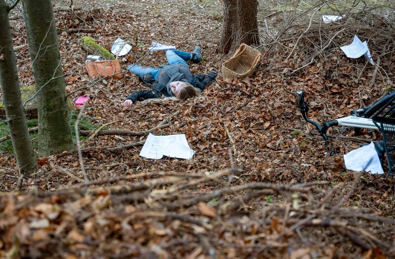 Eine weibliche Leiche (Komparsin) liegt im Wald. Die Frau muss mit dem Fahrrad gestürzt sein. Um sie herum liegen einige Blätter Papier. – Bild: ARD/​Thomas Neumeier
