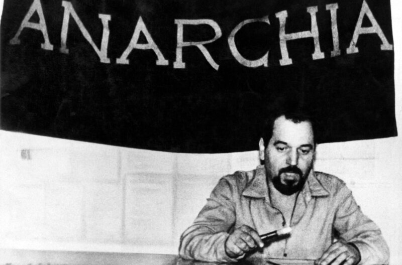 Der italienische anarchistische Aktivist Giuseppe Pinelli in den 60er Jahren: hinter ihm eine Flagge, auf der „Anarchie“ steht – Bild: Mondarori Portfolio/​Getty Images