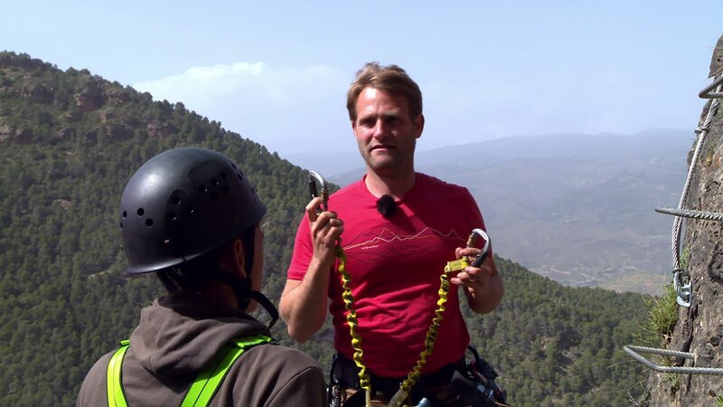 Coach Tobi erklärt den Gurt und die Sicherung, bevor die Sechs an den Klettersteig an der Steilwand dürfen. – Bild: hr/​E+U TV Film- und Fernsehproduktion