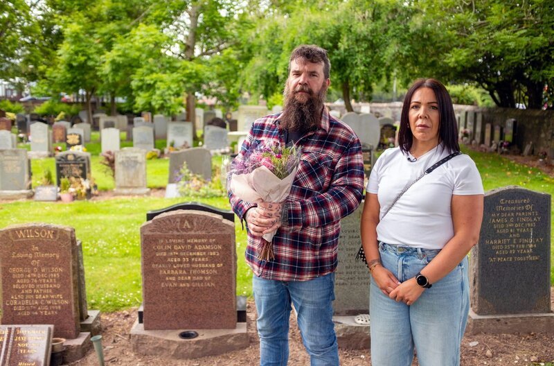 Evan und Gill Adamson am Grab ihres Vaters in Aberdeen, Schottland. Sie waren noch Kleinkinder, als ihr Vater Colin Adamson 1983 in Deutschland ermordet wurde. – Bild: Kobalt Documentary