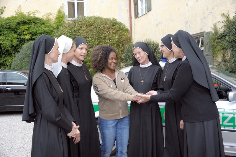 „Um Himmels Willen“, „Sorgenkind.“ Ein Musikvideo, bei dem Schwester Lela mitgewirkt hat, mausert sich im Internet überraschend zum Publikumshit. Anstatt den Erfolg zu genießen, ist Lela zum Weinen zumute. Sie befürchtet, dass durch das mediale Interesse ihre nigerianische Verwandtschaft auf sie aufmerksam werden und sie gegen ihren Willen heimholen könnte. Tatsächlich taucht bald unangenehmer Besuch in Kaltenthal auf. In der Zwischenzeit ist Bürgermeister Wöller damit beschäftigt, die Liste seiner Lebensträume abzuarbeiten.Im Bild (v.li.): Emanuela von Frankenberg (Agnes Schwandt), Julia Heinze (Maria Gasser), Janina Hartwig (Hanna Jakobi), Denise M?Baye (Lela), Karin Gregorek (Felicitas Meier), Andrea Sihler (Schwester Hildegard), Gaby Dohm (Louise von Beilheim). – Bild: ORF/​Kineos/​Jacqueline Krause-Burberg