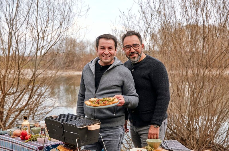 Ali Güngörmüş und Adnan Maral zusammen am Picknick-Grill direkt am Lechufer. Weiteres Bildmaterial finden Sie unter www.br-foto.de. – Bild: BR/​Yalla Productions GmbH/​Marian Mok