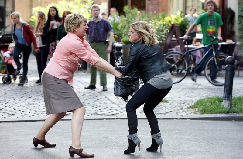 Elisabeth Krutsch (Heike Jonca, l.), Besitzerin eines Schreibwarenladens, geht auf Jeanette Biedermann (Jeanette Biedermann, r.) los. Sie hat ihre Einkäufe in Höhe von 150 Euro nicht bezahlt. Julia Klug (Friederike Kempter, im HG mit Baby Ellie) wird zufällig Zeuge des Angriffs. – Bild: NDR/​ARD/​Daniela Incoronato