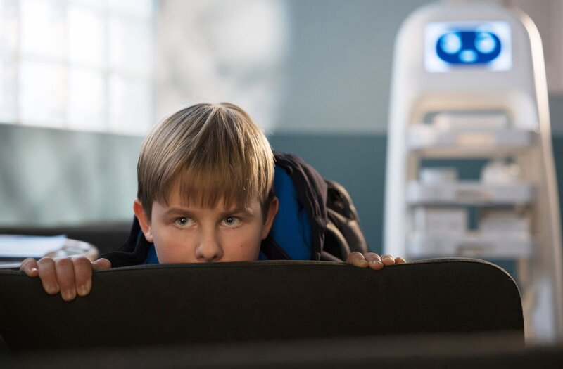 Max Brentano (Ben Grünberg) hat sich in die Sachsenklinik geschlichen, um einen bestimmten Patienten zu besuchen. Da dies von seinem Vater verboten wurde, muss er sich nun vor ihm verstecken. Doch diese Rechnung hat er ohne Pflegeroboter Berta gemacht, der ihn entdeckt. – Bild: MDR/​Saxonia Media/​Rudolf Wernicke