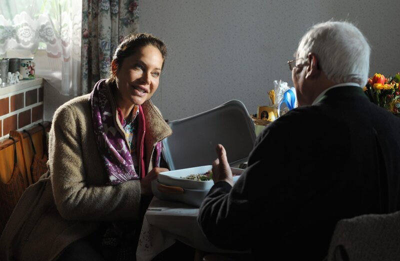 Trixi freut sich, dass sie Senior Kreitner mit „Essen dahoam“ von ihrer Kochkunst überzeugen kann. Von links: Trixi Preissinger (Doreen Dietel) und Herr Kreitner (Hans Hofmann). – Bild: BR/​Marco Orlando Pichler