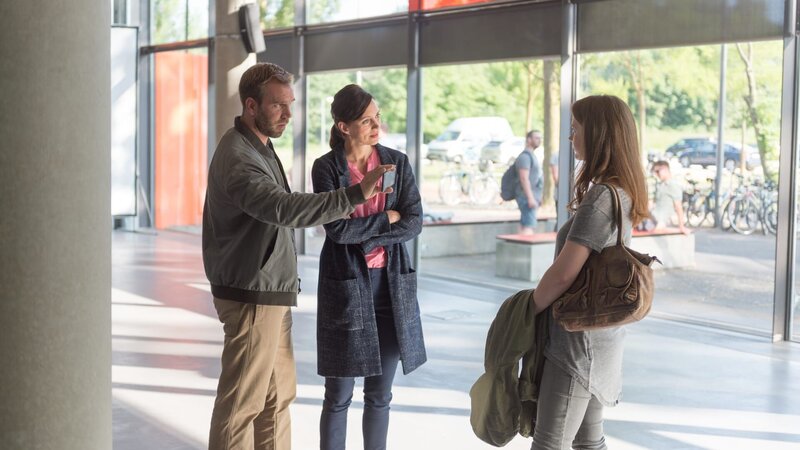 Lars Pöhlmann (Dominic Boeer, l.) und Karoline Joost (Nike Fuhrmann, M.) haben herausgefunden, dass Paula Liedke (Laura Vietzen, r.) am Vorabend mit dem toten Leon Richter den Abend verbracht hat. Ein Handyfoto zeigt, wie Leon Paula zärtlich küsst. Besonders pikant: Paula ist die Freundin von Leons Kollegen und ehemals bestem Freund Malte Röper. Hat der die beiden gesehen und Leon aus Eifersucht umgebracht? – Bild: ZDF /​ Meyerbroeker