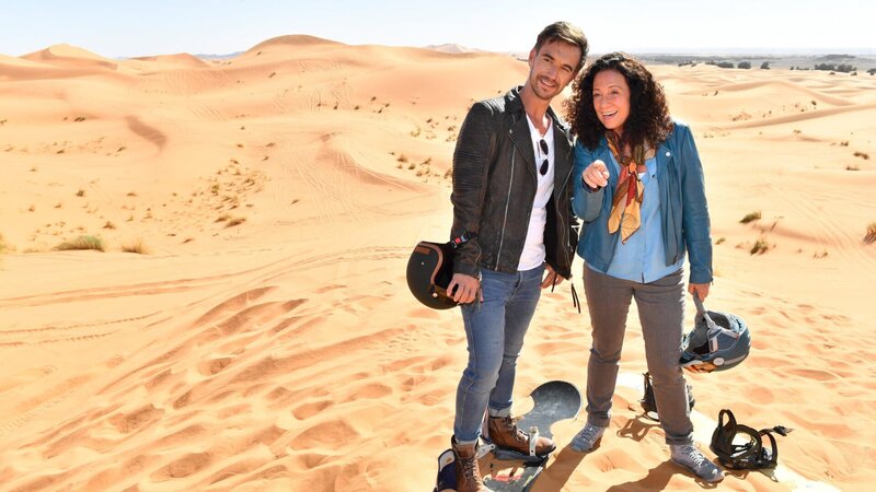 Hanna Liebhold (Barbara Wussow, r.) ist es gelungen, Kapitän Max Parger (Florian Silbereisen, l.) zu einem „Skiausflug“ in die goldenen Sanddünen zu überreden. – Bild: ZDF