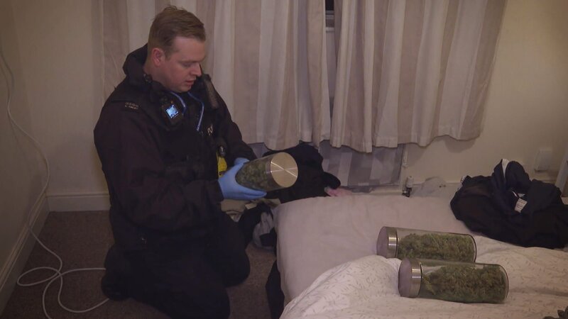 Polizeibeamter mit einem Glas Marihuana in der Hand. – Bild: Warner Bros. Discovery