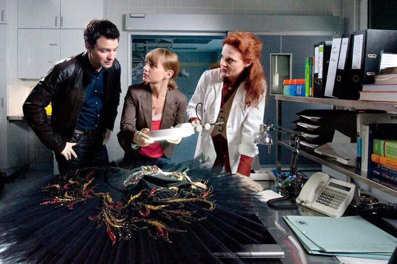 „Soko Kitzbühel“, „Sterbender Schwan.“ Die Primaballerina Tatjana Ulitskaja bricht kurz vor Ende einer Aufführung von „Schwanensee“, die der Juwelier Ulrich Laurenz zum Geburtstag seiner Frau Irina in seinem Schloss organisiert hat, tot zusammen. Hat der Choreograf und Manager der Ballettgruppe Sascha Binder etwas mit dem Mord zu tun, oder gar die Kostümbildnerin Sonja Michailowa, eine Kindheitsfreundin der Ballerina? Auch Irina Laurenz liefert der Soko ein Mordmotiv: Sie vermutete eine Affäre zwischen ihrem Mann und der Tänzerin. Als in die Pathologie eingebrochen und Dr. Haller niedergeschlagen wird, erkennt Karin einen Lösungsansatz.Im Bild (v.li.): Jakob Seeböck (Lukas Roither), Kristina Sprenger (Karin Kofler), Christine Klein (Dr. Haller). – Bild: ORF 1