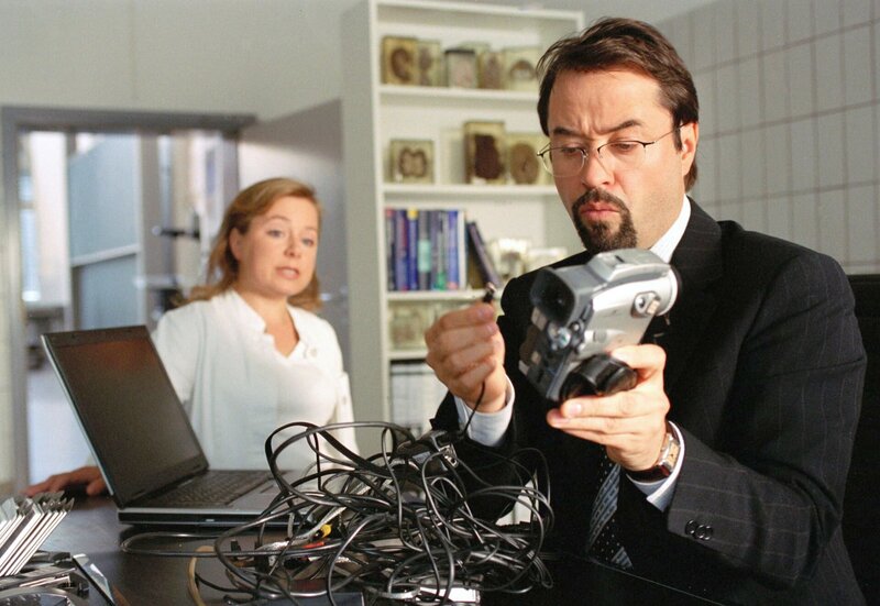 ARD/​WDR TATORT, „Eine Leiche zuviel“, Fernsehfilm Deutschland, Regie: Kaspar Heidelbach, Buch: Dorothee Schön und Georg Schott. Männer und Technik. Silke Haller alias „Alberich“ (ChrisTine Urspruch) ist skeptisch, dass ihr Chef es schafft, die Videokamera in Betrieb zu nehmen. Prof. Karl-Friedrich Boerne (Jan Josef Liefers) will sich den Film angucken, der anlässlich des Abschlussfestes am Anatomischen Institutes gedreht wurde. – Bild: WDR/​Jürgen Thiele