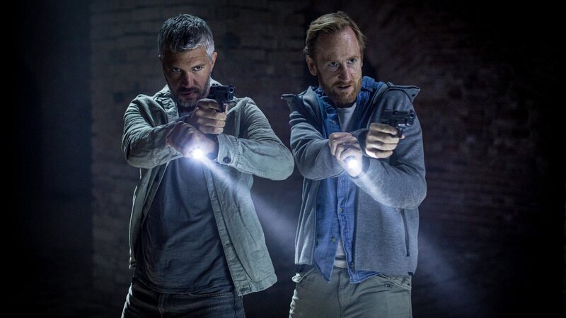 Alexander (Nicolai Cleve Broch, l.) und sein Vorgesetzter Stenmark (Gustaf Hammarsten, r.) können den flüchtigen Täter im dunklen Verlies stellen. – Bild: ZDF