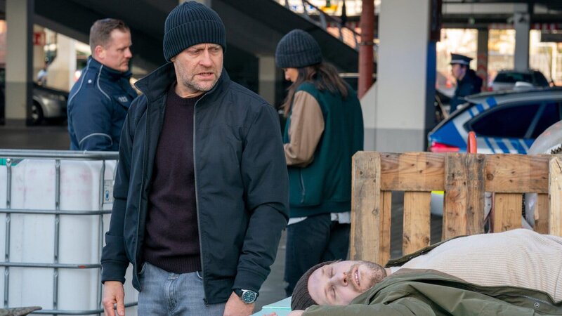 Robert (Jürgen Vogel, 2.v.l.) begutachtet den Tatort und die Leiche von Hannes Seidel (Nils Malten, r.), während Mavi (Aybi Era, 2.v.r.) im Hintergrund mit einem Polizeibeamten spricht. – Bild: ZDF