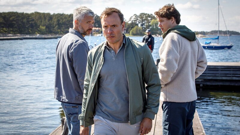 Alexander (Nicolai Cleve Broch, l.) und sein Kollege Welpe (Julius Fleischanderl, r.) wundern sich über das Verhalten des Star Golfers Theo Skoog (Björn Bengtsson, M.). Verheimlicht er etwas vor der Polizei? – Bild: ZDF