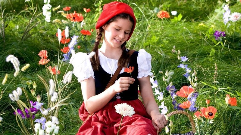 Rotkäppchen (Kathleen Frontzek) freut sich über die Blumenpracht im Wald. Sie will der kranken Großmutter einen schönen Strauß bringen. – Bild: ZDF/​Steffen Junghans/​KiKA