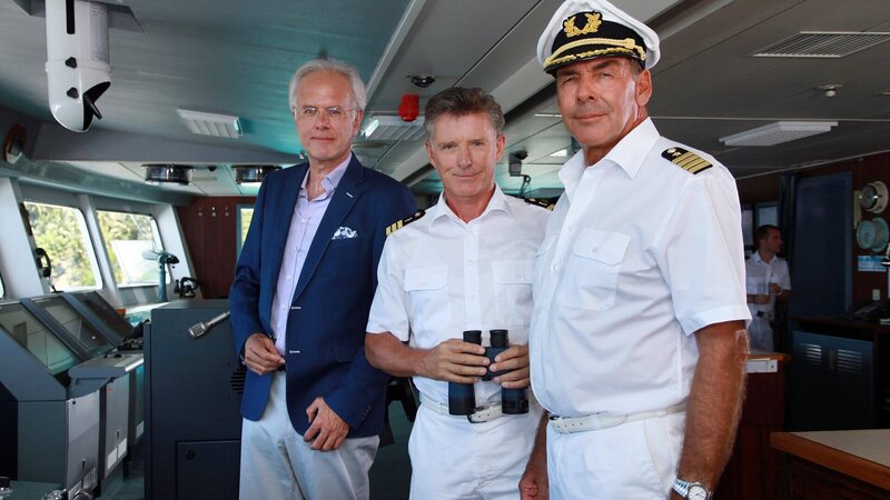 Auf der „Traumschiff“-Reise nach Macau ist auch Oskar Schifferle (Harald Schmidt, l.) wieder mit an Bord. Dr. Sander (Nick Wilder, M.) und Kapitän Burger (Sascha Hehn, r.) freuen sich. – Bild: ZDF