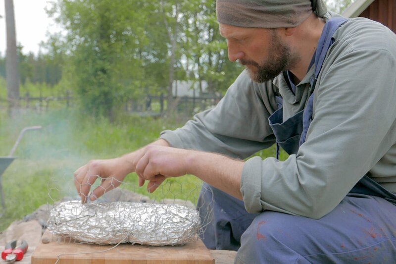 Samppa Suutarinen prüft den Räuberbraten, der unter der Erde gegart wird. – Bild: Fabian Runtenberg