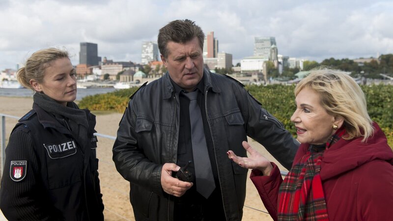 Eine ältere Dame (Dagmar Berghoff, r.) hat beim Gassi gehen mit ihrem Hund eine schwer verletzte Frau am Elbufer entdeckt und die Polizei gerufen. Franzi (Rhea Harder, l.) und Hans (Bruno F. Apitz, M.) befragen die Dame, ob ihr irgendetwas Ungewöhnliches aufgefallen ist. – Bild: ZDF