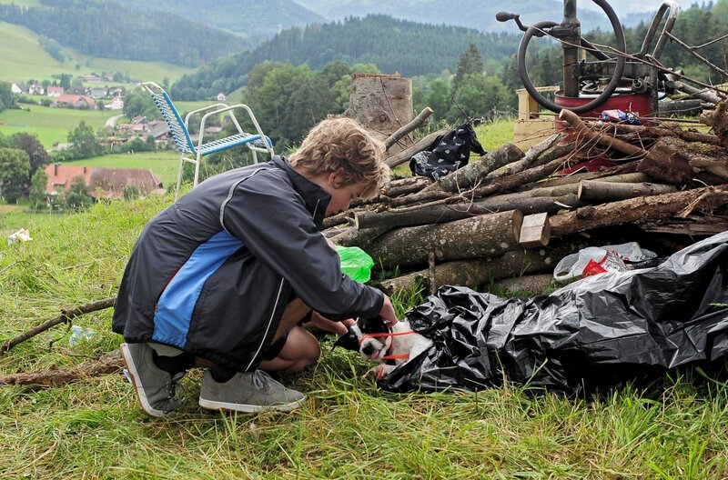 Tim (Noah Boehm) versucht eilig, Cookie aus dem Plastikmüll zu befreien. – Bild: SWR/​Maria Wiesler