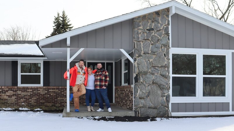 From left to right: Host David Bromstad, Brittany Godlewski, and Coty Nail pose for a picture outside of House 1, Gopher Hill, as seen on My Lottery Dream Home, Season 17. – Bild: Warner Bros. Discovery