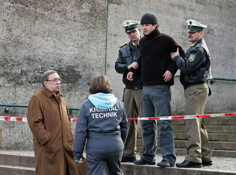 Taxiunternehmer Georg Sendler (Tobias Oertel, oben Mitte) wird an der Absperrung von Beamten festgehalten. Schmücke (Jaecki Schwarz, links) kommt dazu. – Bild: rbb/​MDR/​Saxonia Media/​Frauendorf