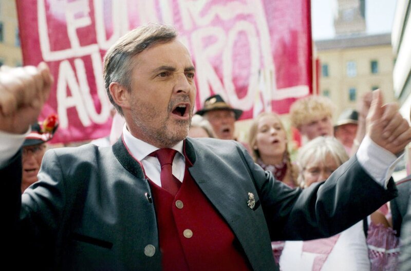 Der Tiroler Vizebürgermeister Gernkönig (Harald Schrott) verspricht sich Wählerstimmen von der Debatte um die Lederhose und heizt sie kräftig an. – Bild: ARTE,ORF /​ ORF/​e&a film