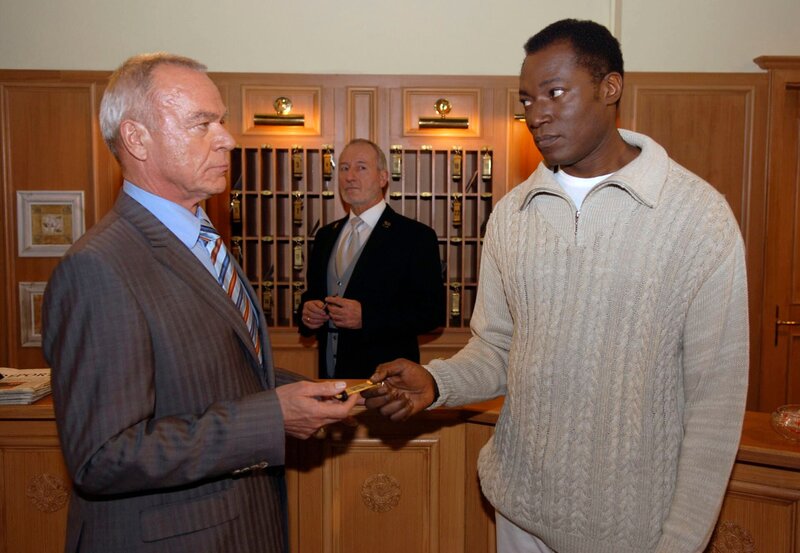 10 Uhr im Ersten. Werner (Dirk Galuba, l.) gibt Joshua Obote (Aloysius Itoka, r.) ein Zimmer am Fürstenhof. Alfons (Sepp Schauer, M.) fragt sich indes, ob das gut geht. – Bild: ARD/​Jo Bischoff