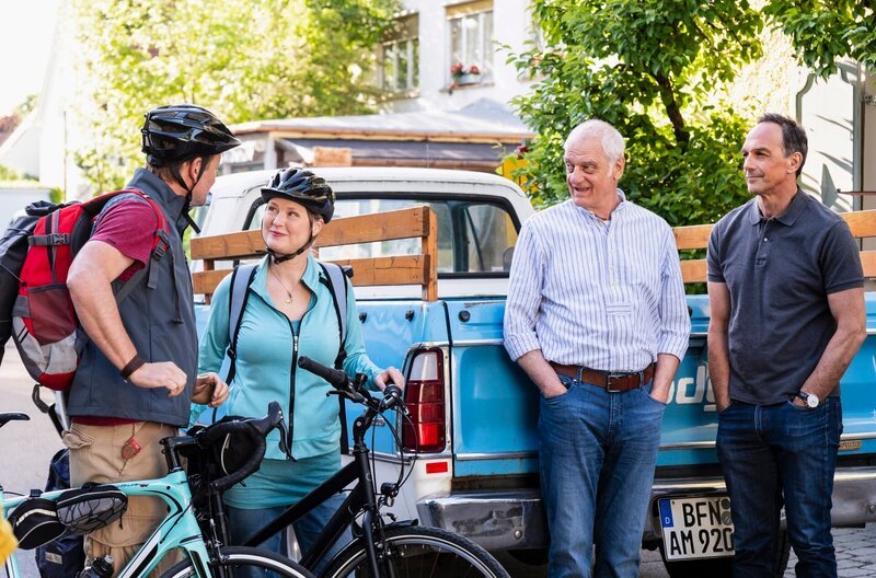 Gregor und Vera wollen sich von Joseph und Mike verabschieden, bevor ihre Radtour losgeht. Von links: Gregor (Holger Matthias Wilhelm), Vera (Sybille Waury), Joseph (Michael Vogtmann) und Mike (Harry Blank). – Bild: BR/​Lena Semmelroggen