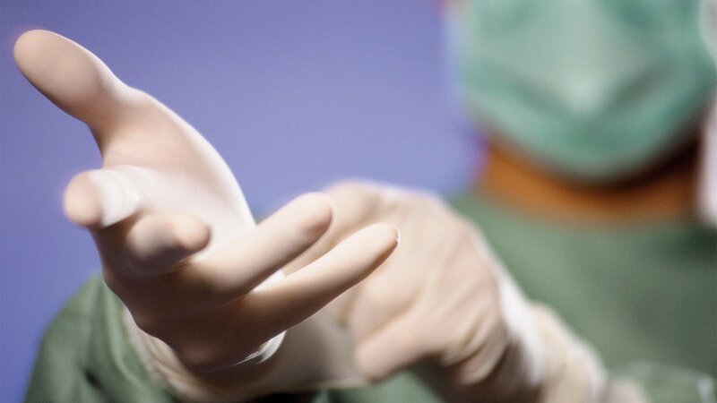 Surgeon Putting on Gloves --- Image by – Bild: Corbis.